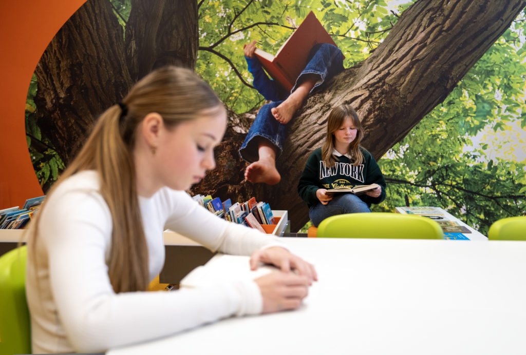 Leerlingen die lezen aan een tafel en in een leeshoek. 