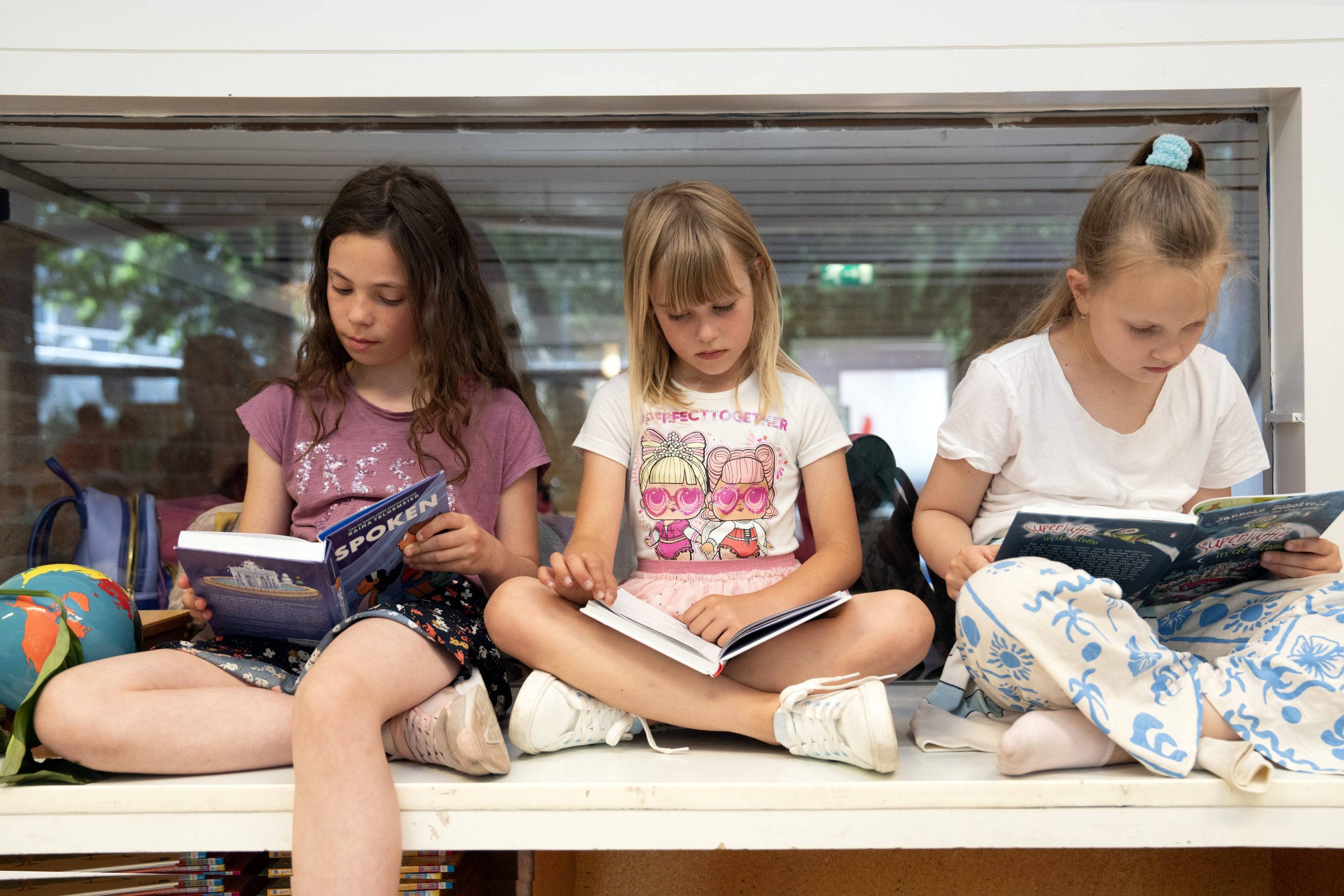 Leerlingen zitten te lezen in een vensterbank, met achter hen het raam.