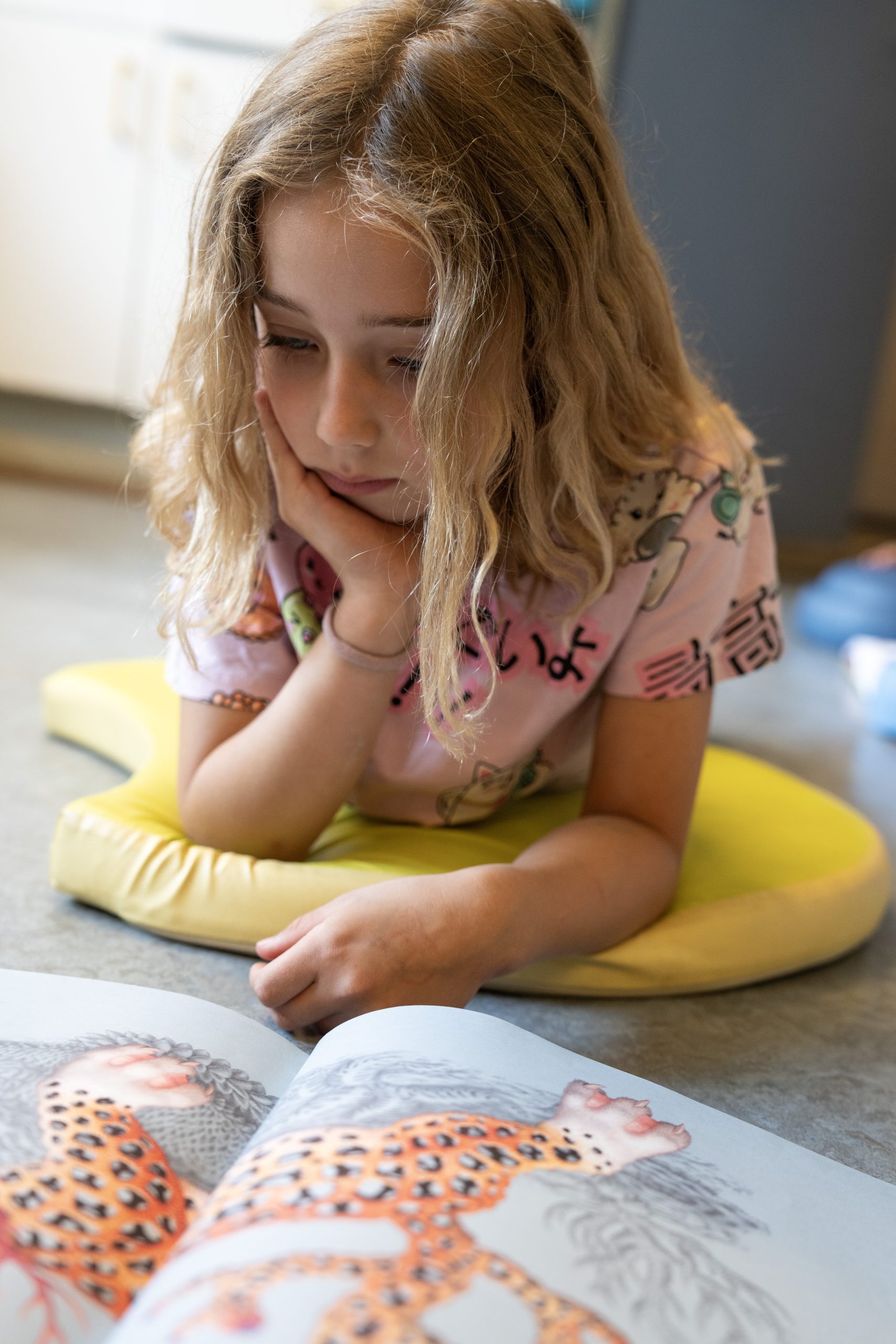 Kind leest een boek, liggend op de grond