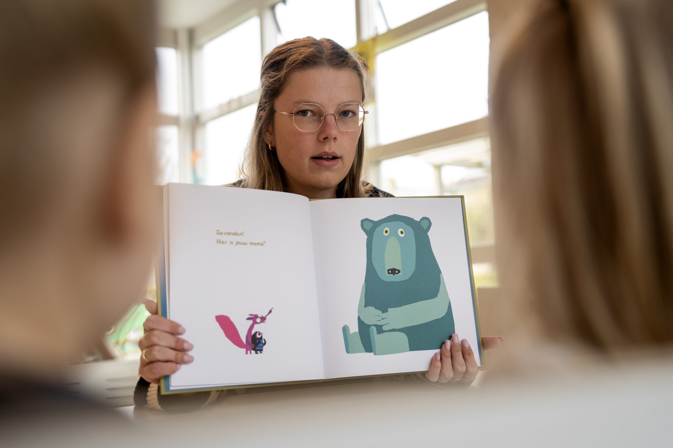 Docent leest voor, doorkijk langs kinderen