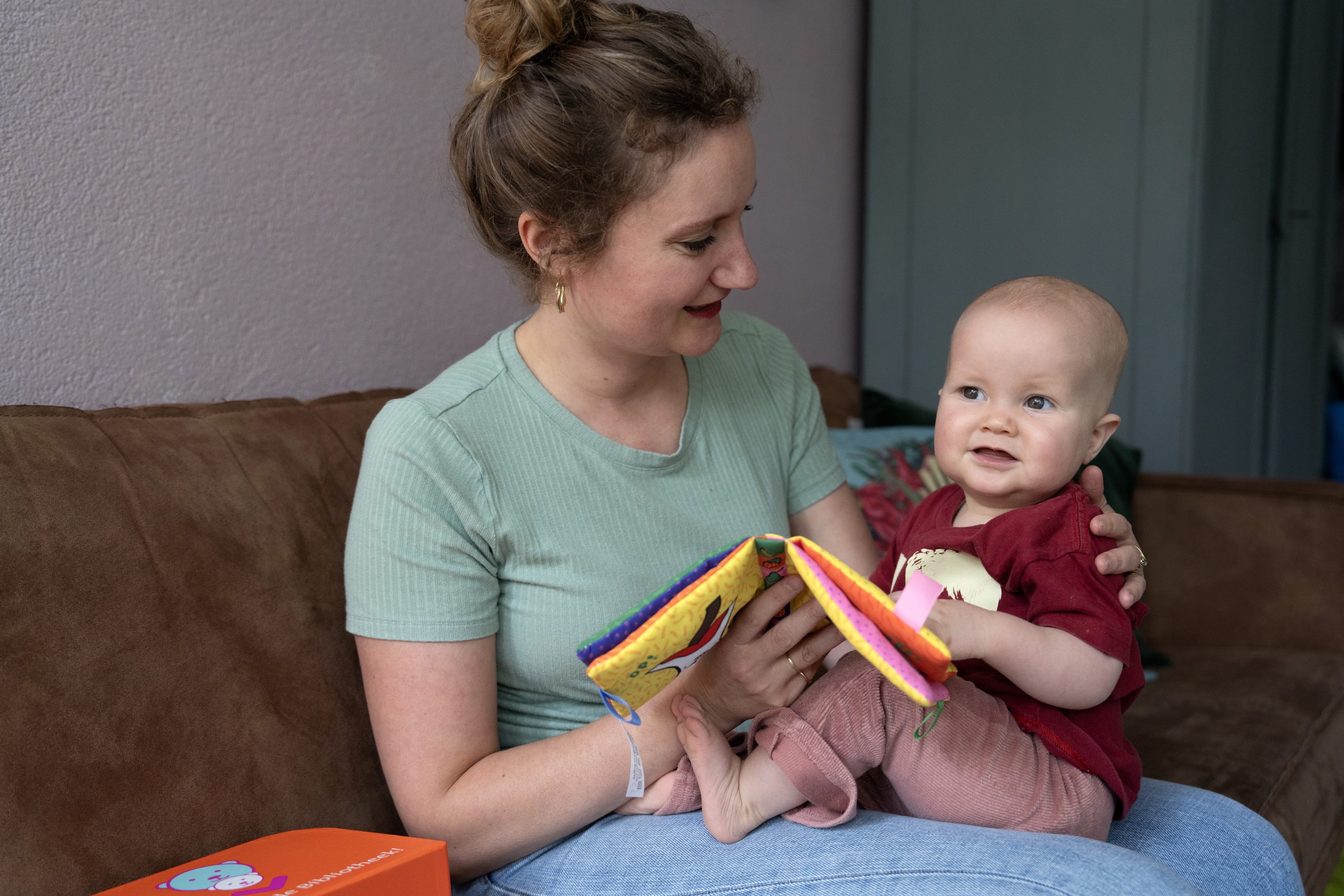 Moeder leest baby voor op bank.