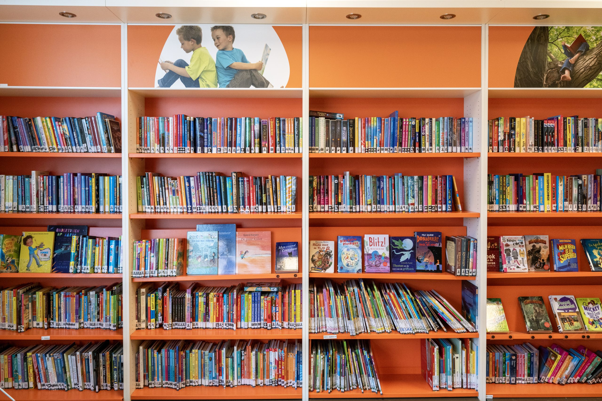 Oranje boekenkasten vol boeken in een schoolbibliotheek - rijkte thema's