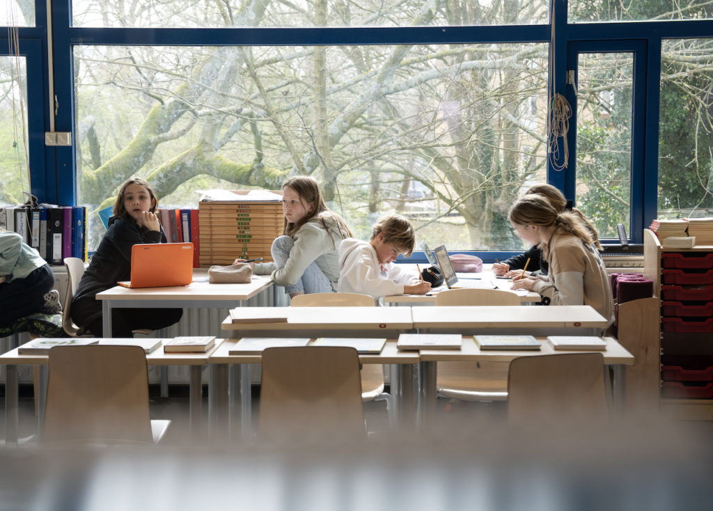 Kinderen werken aan een tafel voor een groot raam - rijke thema's