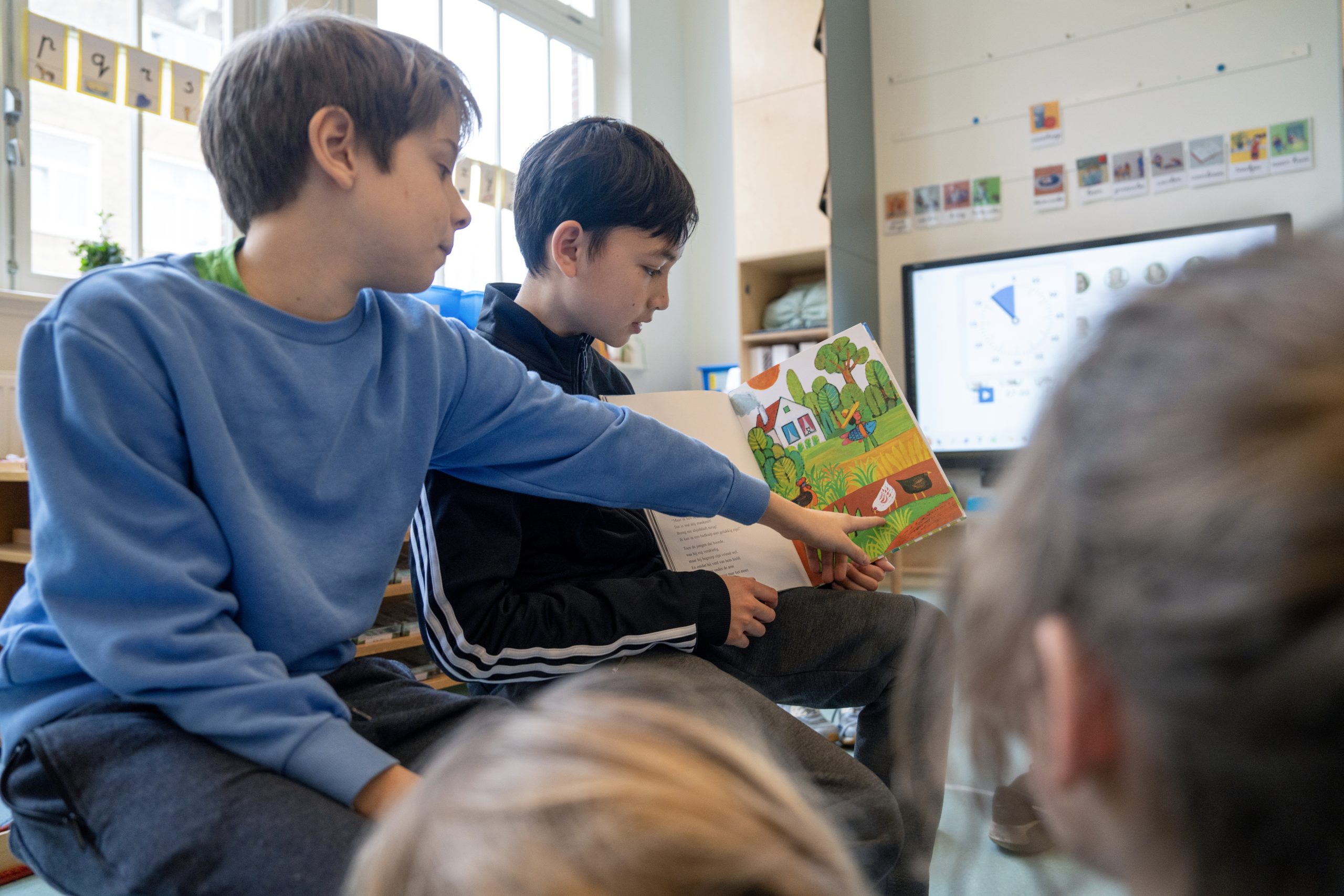 Jongens lezen samen boek voor in de klas