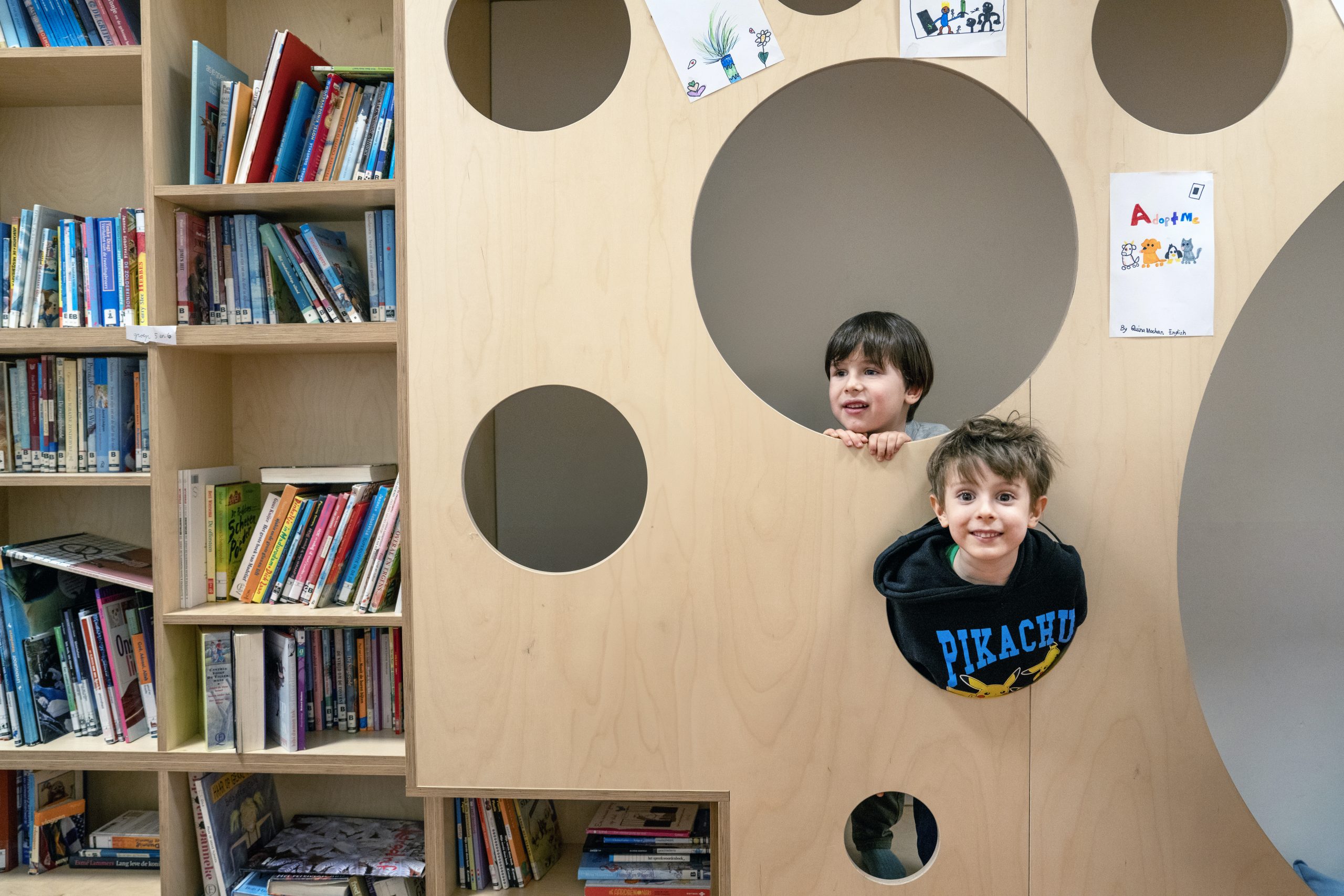 Kinderen in een speeltoestel naast de boekenkast.