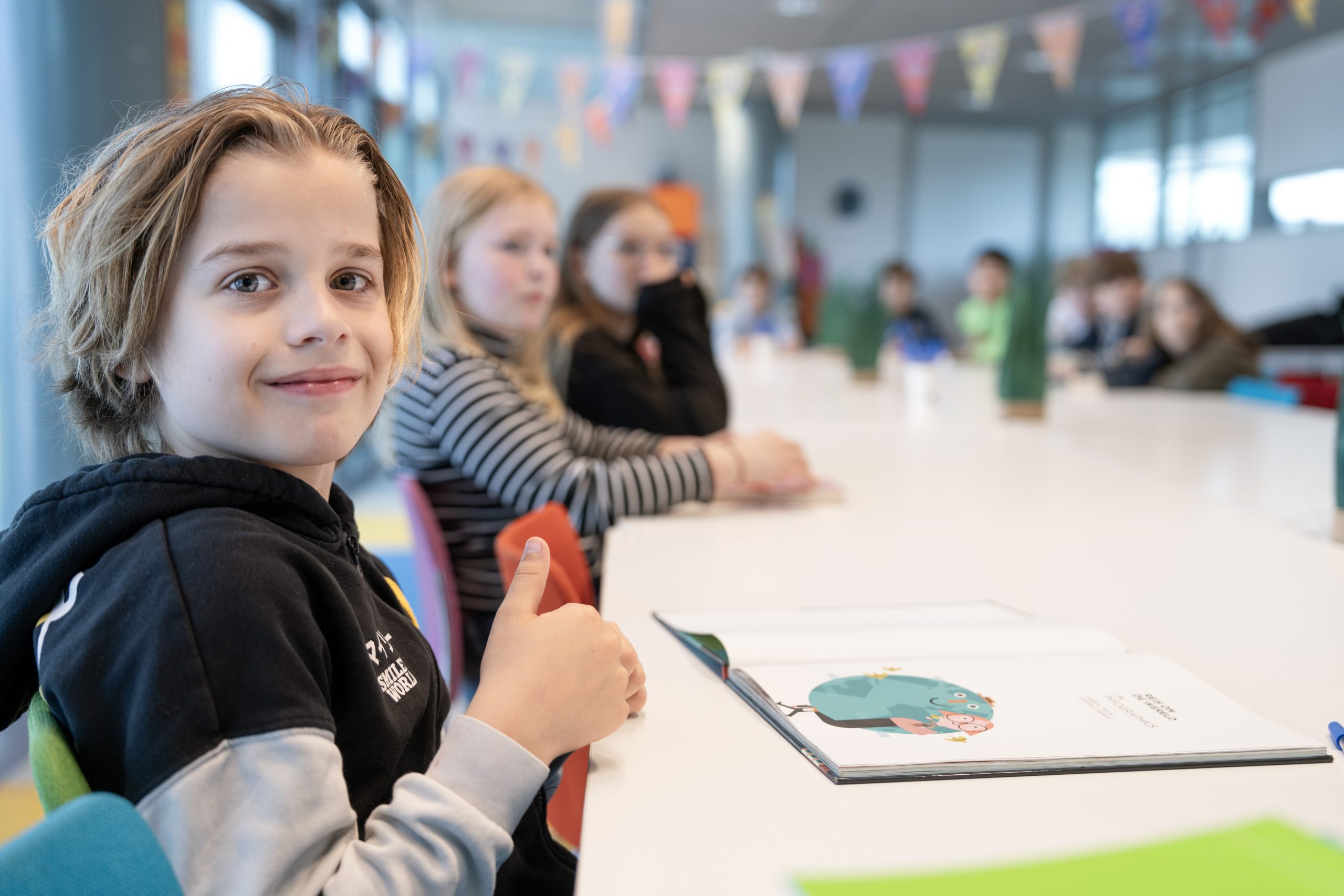 Jongen in een klaslokaal steekt zijn duim omhoog naar de camera - rijke thema's