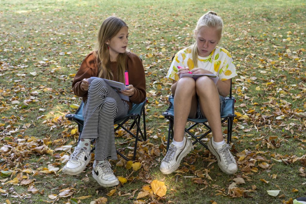 Meisjes zitten buiten op klapstoeltjes te lezen - rijkte thema's