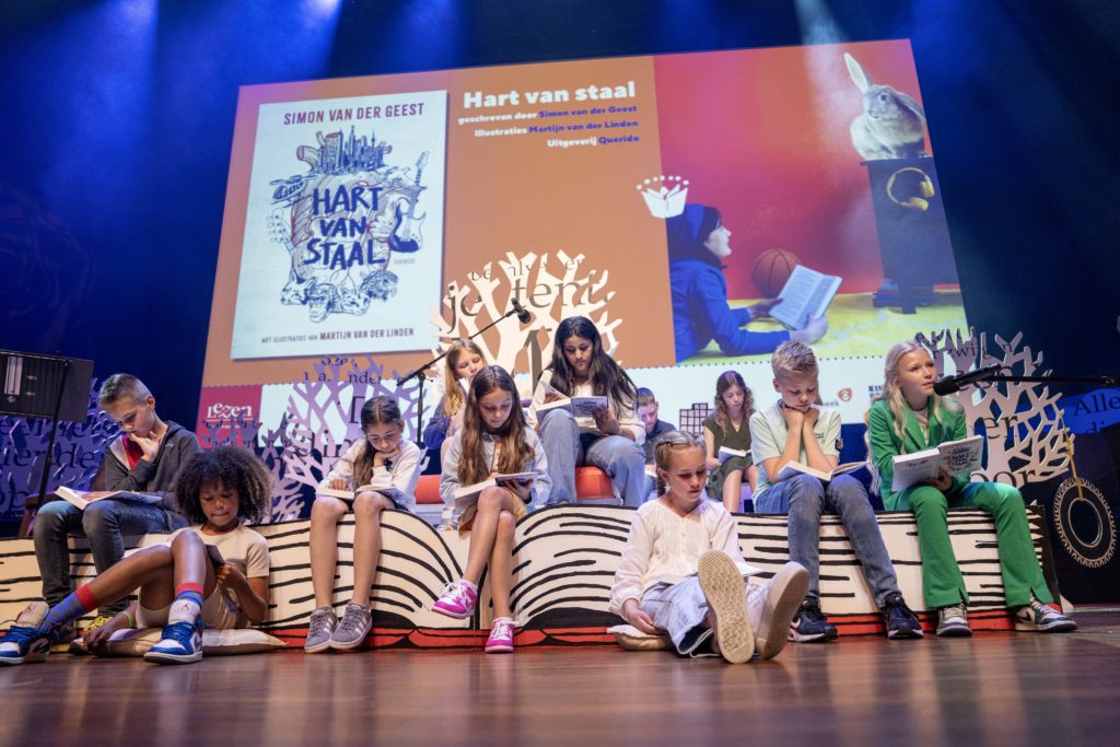 Kinderen lezen voor tijdens De Nationale Voorleeswedstrijd, op podium.