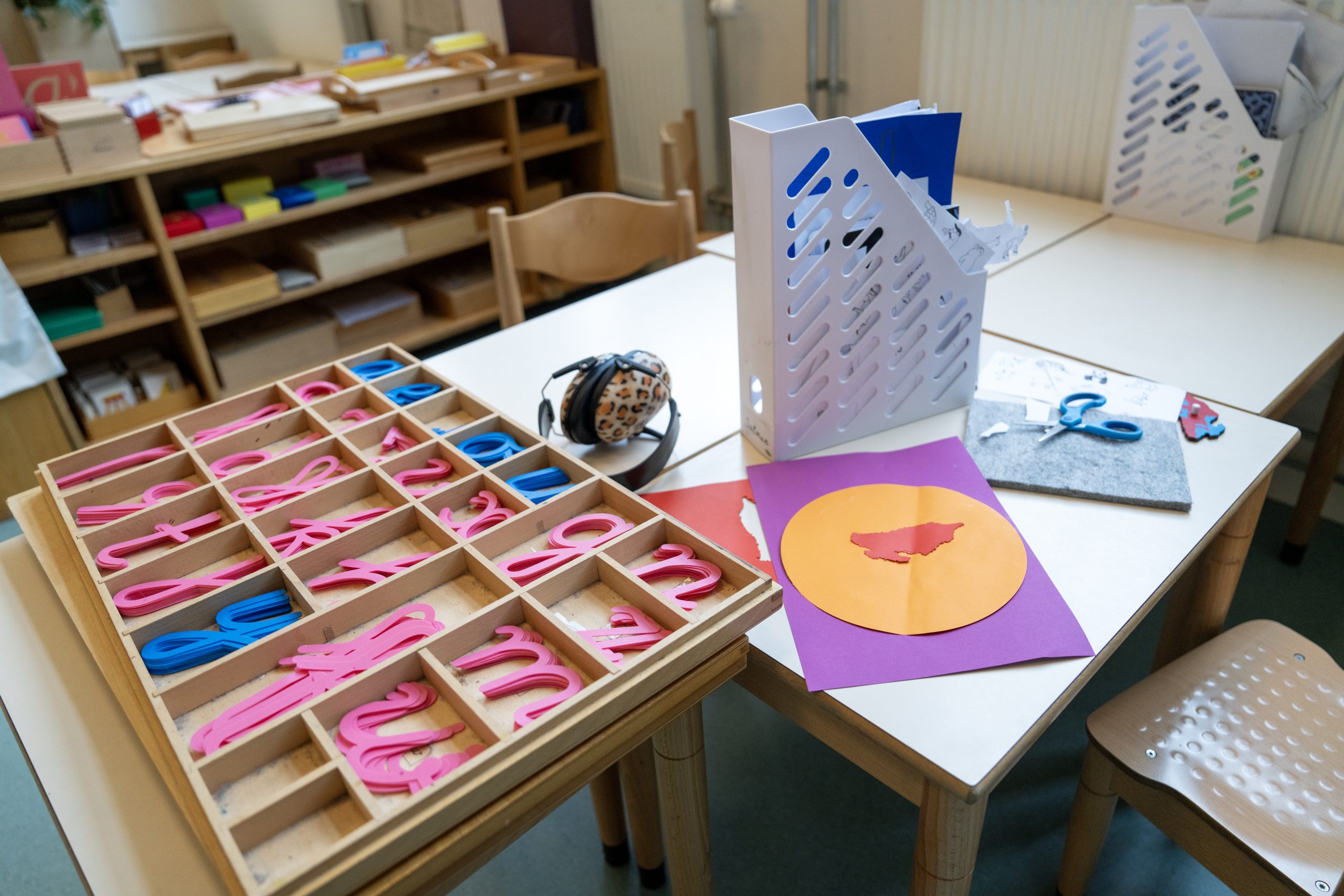 Tafel met daarop een bord met schrijfletters in blauw en roze, een ordner en een koptelefoon. 